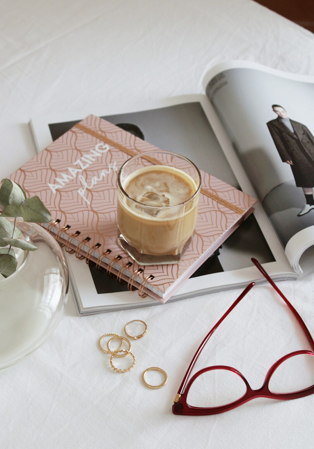 Notebook, reading glasses and a cup of coffee on a wooden desk